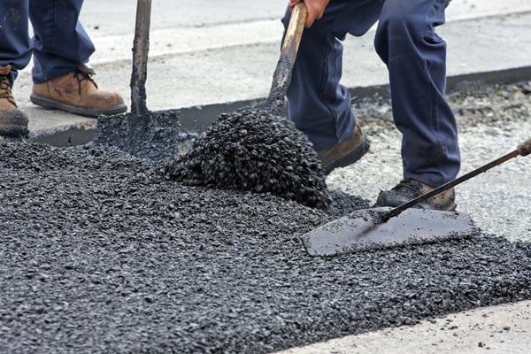 Shovelling And Raking Hot Asphalt On A Road Repair Site